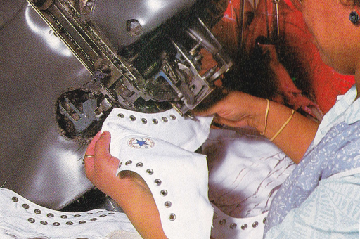 A worker pokes metal eyelet washers into an All Star at the old Converse factory in North Carolina. Scanned from the book “How Are Sneakers Made?” by Henry Horenstein (1993 Simon and Schuster)