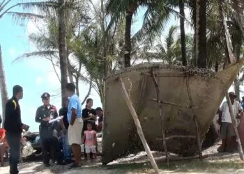 A picture made available on 24 January 2016 shows a Thai police officer and villagers inspecting a piece of a suspected airplane wreckage at a beach in Pak Phanang district, Nakhon Si Thammarat. (Source: EPA)