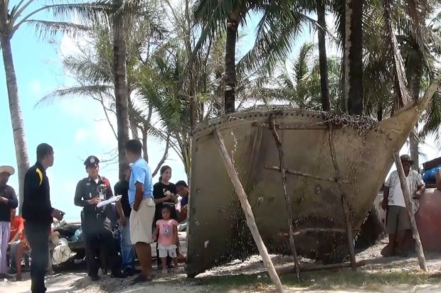 A picture made available on 24 January 2016 shows a Thai police officer and villagers inspecting a piece of a suspected airplane wreckage at a beach in Pak Phanang district, Nakhon Si Thammarat. (Source: EPA)