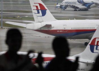 In this photo taken on Saturday, March 5, 2016, Malaysia men are silhouetted against taxied Malaysia Airlines' planes in Kuala Lumpur International Airport in Sepang, Malaysia. Malaysia's transport minister said on Monday, March 14, 2016, that two plane pieces found in Mozambique will be sent to Australia to verify if they belong to Malaysia Airlines Flight 370. (AP Photo/Joshua Paul)