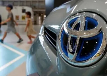 Visitors walk past a logo of Toyota Motor Corp on a Toyota Prius hybrid vehicle at the company's showroom in Tokyo August 5, 2014. REUTERS/Yuya Shino/File Photo
