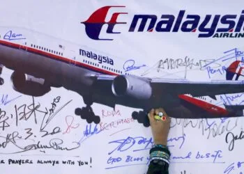 A woman writes a message on a board for passengers onboard missing Malaysia Airlines Flight MH370 and their family members, at Dataran Merdeka in Kuala Lumpur March 22, 2014. Two weeks after the airliner went missing with 239 people on board, officials are bracing for the "long haul" as searches by more than two dozen countries turn up little but frustration and fresh questions. REUTERS/Samsul Said (MALAYSIA - Tags: DISASTER TRANSPORT)