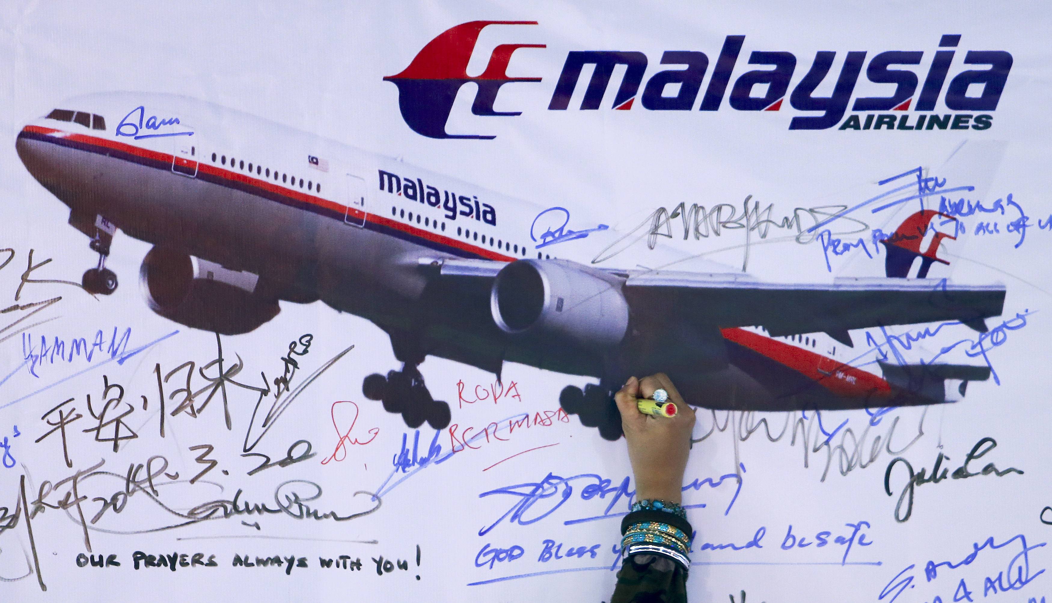 A woman writes a message on a board for passengers onboard missing Malaysia Airlines Flight MH370 and their family members, at Dataran Merdeka in Kuala Lumpur March 22, 2014. Two weeks after the airliner went missing with 239 people on board, officials are bracing for the "long haul" as searches by more than two dozen countries turn up little but frustration and fresh questions. REUTERS/Samsul Said (MALAYSIA - Tags: DISASTER TRANSPORT)